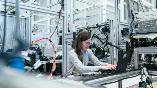 ingénieur électrotechnique instrumentation automatismes qui travaille dans une usine de production sur son ordinateur.