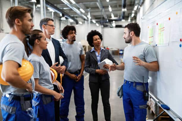 Jeune ouvrier d'usine tenant une présentation sur le développement de la production aux chefs d'entreprise et à ses collègues.